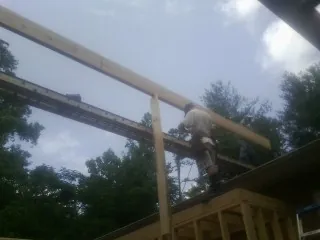 Carpenter setting a ridge beam over a new addition frame — Ice Dam Removal by Roofing Brothers in Haledon
