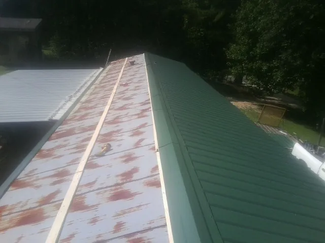 Old rusted panels beside newly installed green metal roofing — Wind Damage Roof Repair by Roofing Brothers in Haledon
