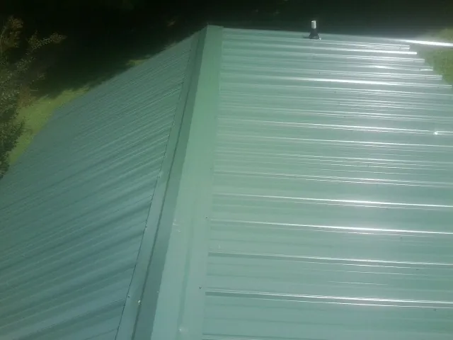 New green metal panels meeting at the ridge of a roof — Flat Roof Repair work by our crew in Haledon