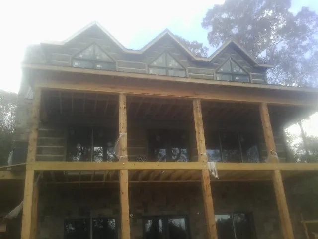 Dormers and porch framing on a large log home under construction — Roof Coating work by our crew in Haledon