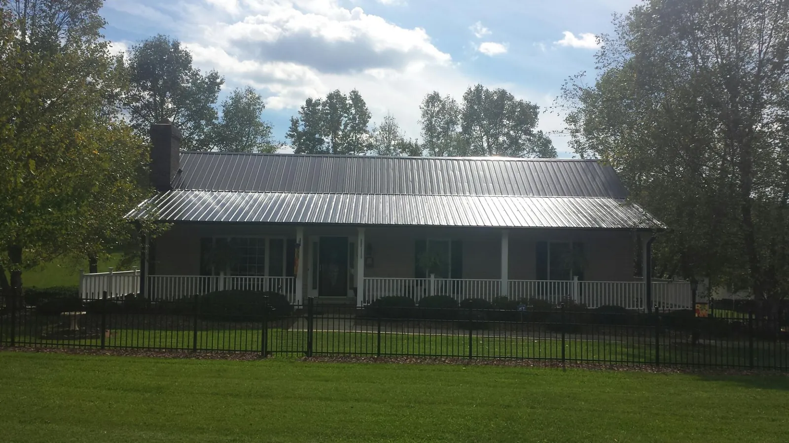 Gray metal roof on a brick ranch with a full width front porch — Gutter Guard Installation work by our crew in Haledon
