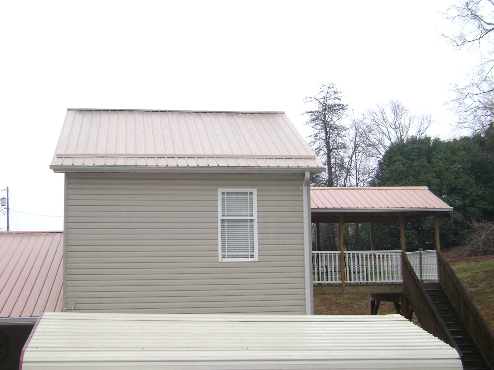 Tan metal roofs on a two story addition and attached porch, from a Roof Replacement job in Haledon